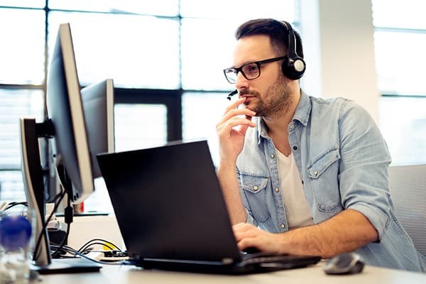 Mann sitzt mit Kopfhörern vor dem Computer | MagicPOS Kassen IT Fachhandel