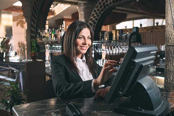 Kellnerin bedient ein Kassensystem in einem Restaurant mit einer freundlichen Miene.